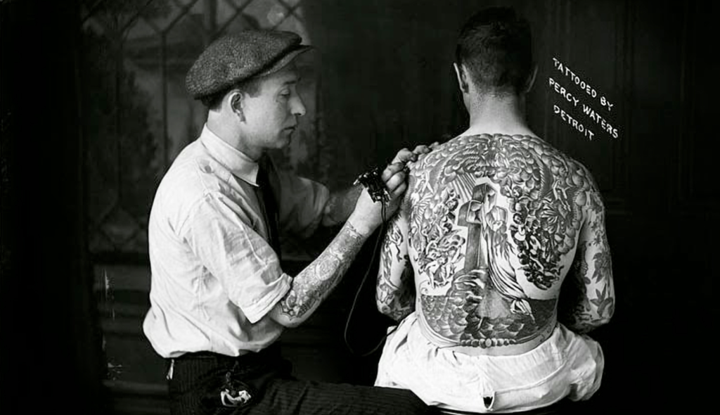 Picture of tattoo artist and person getting tattoo with their body covered in tattoo.